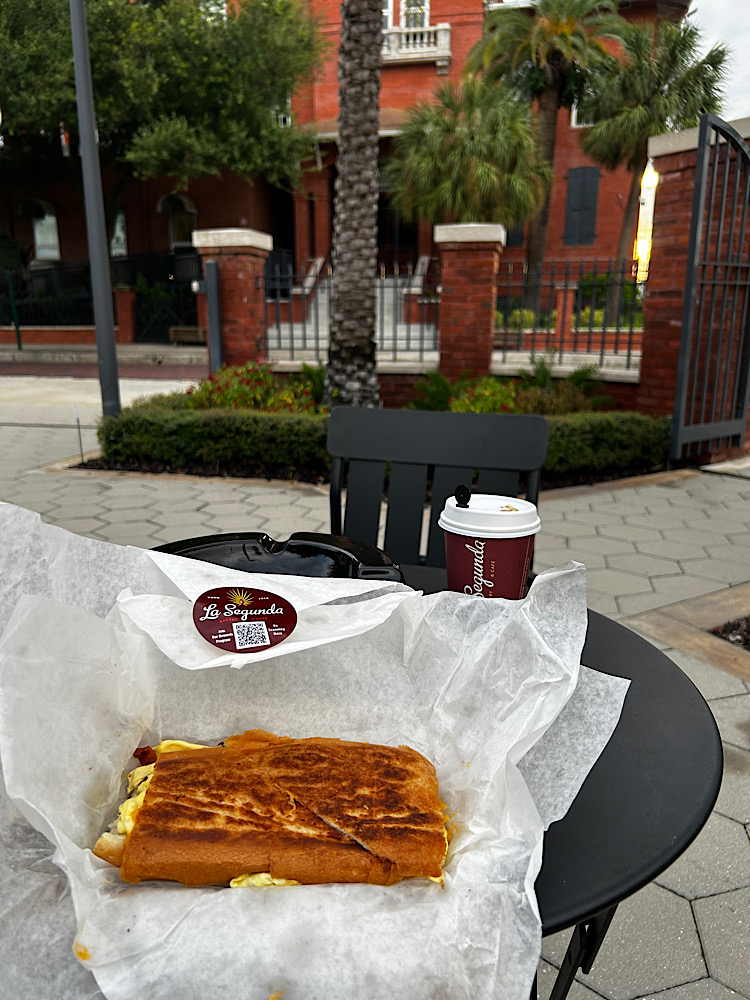 A La Segunda breakfast sandwich and a coffee on an outdoor table